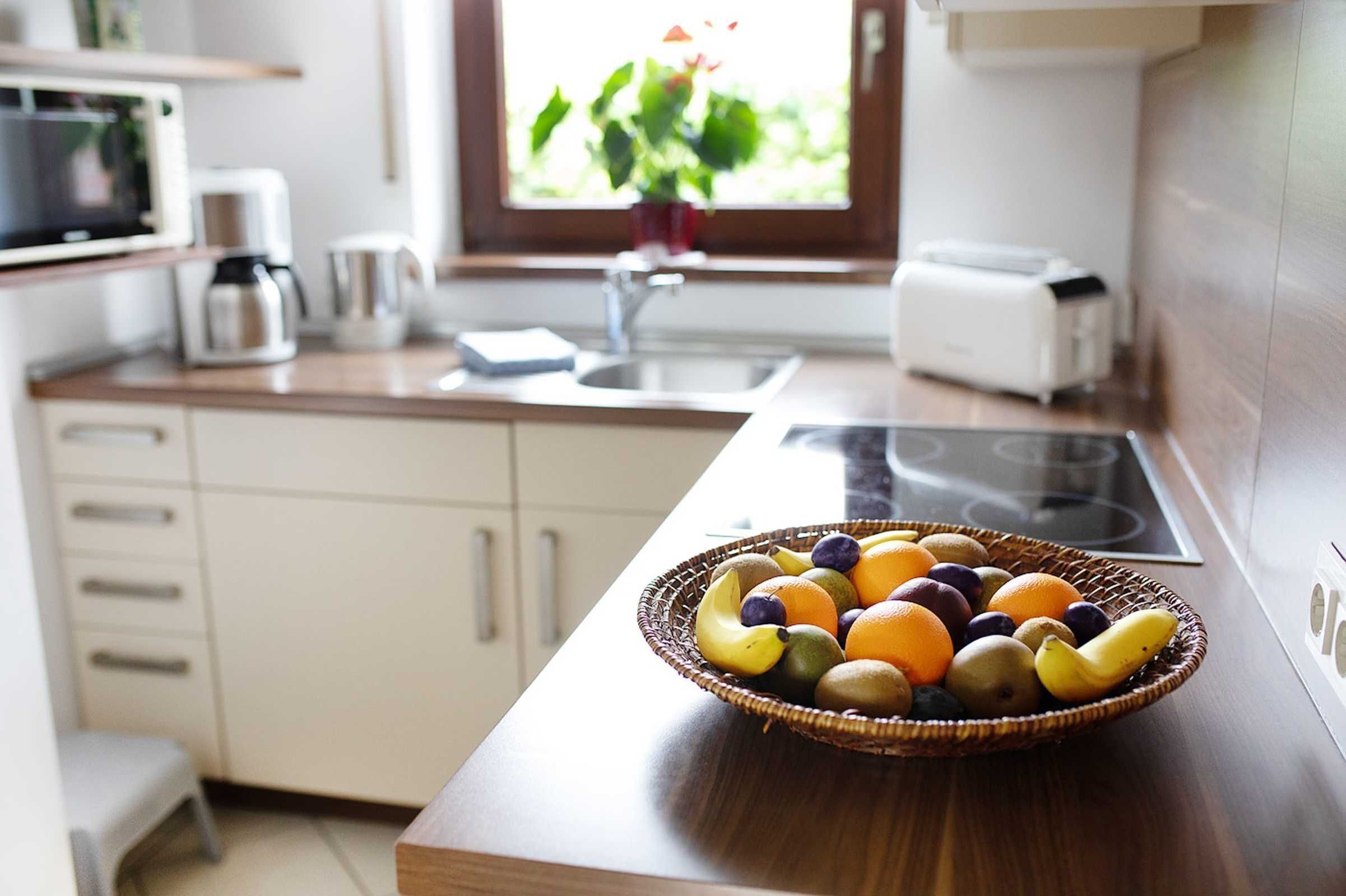 A kitchen with a fruit bowl on the counter, a microwave, a coffee maker, and a toaster.
