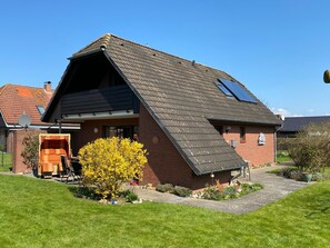 Une maison avec un toit en pente, une cheminée bien visible et une antenne parabolique.