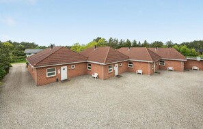 A row of three brick houses with red-tiled roofs, each with a small porch and white outdoor furniture. - Nice home in Rømø with sauna (Rømø)
