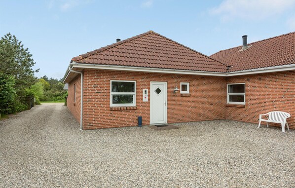 A single-story brick house with a tiled roof, a gravel driveway, and a white door. - Nice home in Rømø with sauna (Rømø)