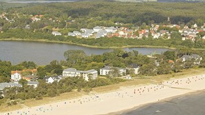 Vista aérea de un pueblo costero con playa, casas y un lago.