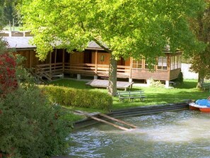 Una baita di legno con una veranda, un piccolo molo e un canale d'acqua.