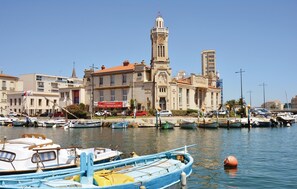 A marina with boats docked, a prominent building with a clock tower, and a clear blue sky. - Stunning apartment in Sète with WiFi (Sète)