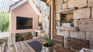 An outdoor seating area with a stone wall, a wooden table, and a built-in grill.