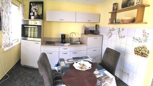 Une cuisine compacte avec un coin repas, comprenant un évier, une cuisinière et des placards.