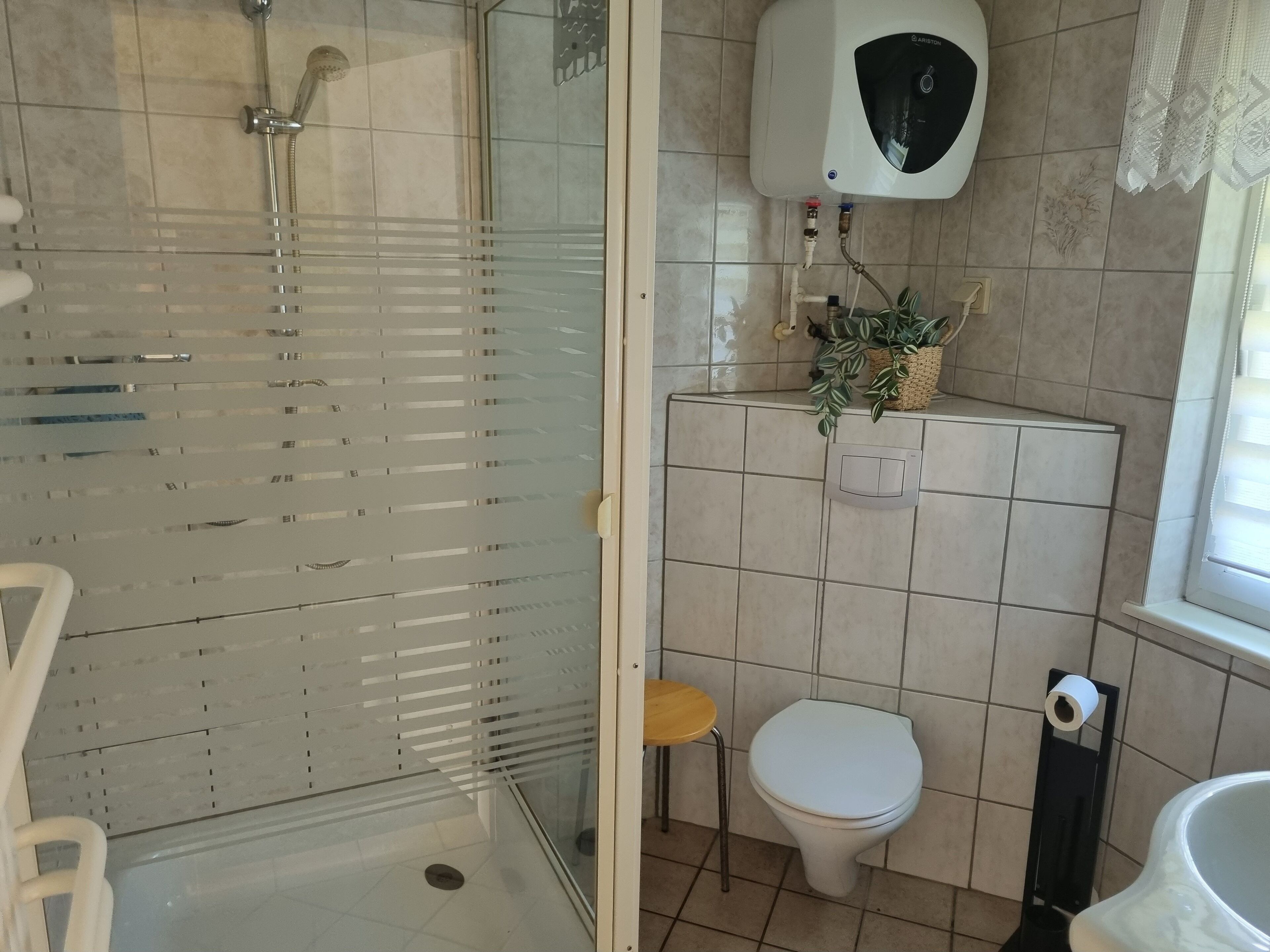 A bathroom with a glass-enclosed shower, a toilet, and a sink.