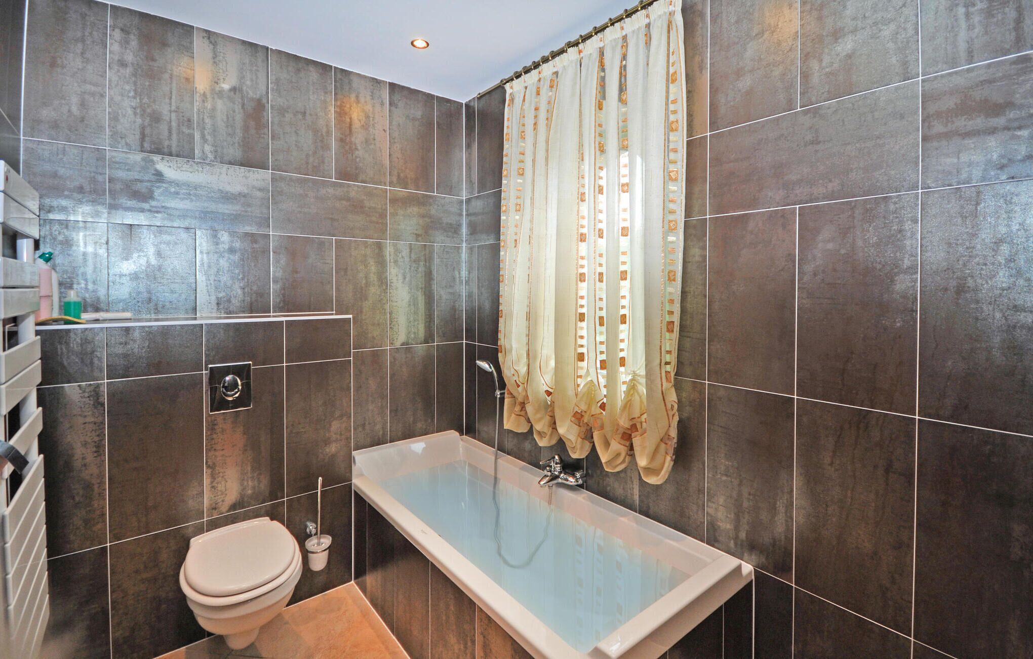 A bathroom with a bathtub, toilet, and a shower curtain.