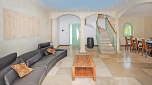 A spacious living area with a leather sofa, a wooden coffee table, and a staircase leading to a dining area. - Stunning home in Saint Raphael (Saint Raphael)
