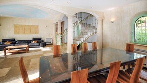 A spacious living area with a glass-top dining table, wooden chairs, a black leather sofa, and a staircase with green railings. - Stunning home in Saint Raphael (Saint Raphael)