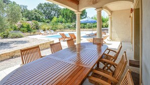 An outdoor patio with a wooden table and chairs, a pool, and lounge chairs. - Stunning home in Saint Raphael (Saint Raphael)
