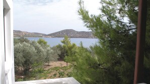 Vista desde una ventana sobre un lago rodeado de árboles y colinas.