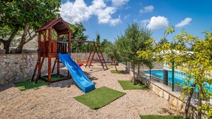 A playground with a slide, swings, and a pool.