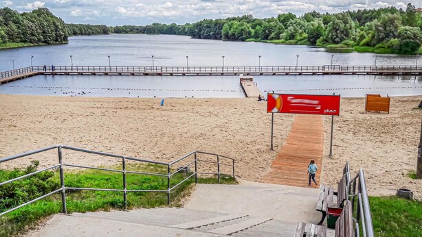 Ein Strand mit einer Holzpromenade, die zu einem Steg führt.