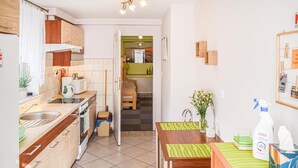 Eine kleine Küche mit Spüle, Herd und Mikrowelle. Ein Essbereich mit Tisch und Stühlen ist zu sehen.