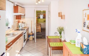 Eine kleine Küche mit Spüle, Herd und Mikrowelle. Ein Essbereich mit Tisch und Stühlen ist zu sehen.