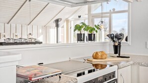 Een moderne keuken met een gasfornuis, een brood op het aanrecht en potplanten op de vensterbank.