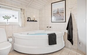 A bathroom with a round bathtub, a toilet, a window with curtains, a framed picture on the wall, and a towel rack. - Beautiful home in Haderslev with WiFi (Haderslev)