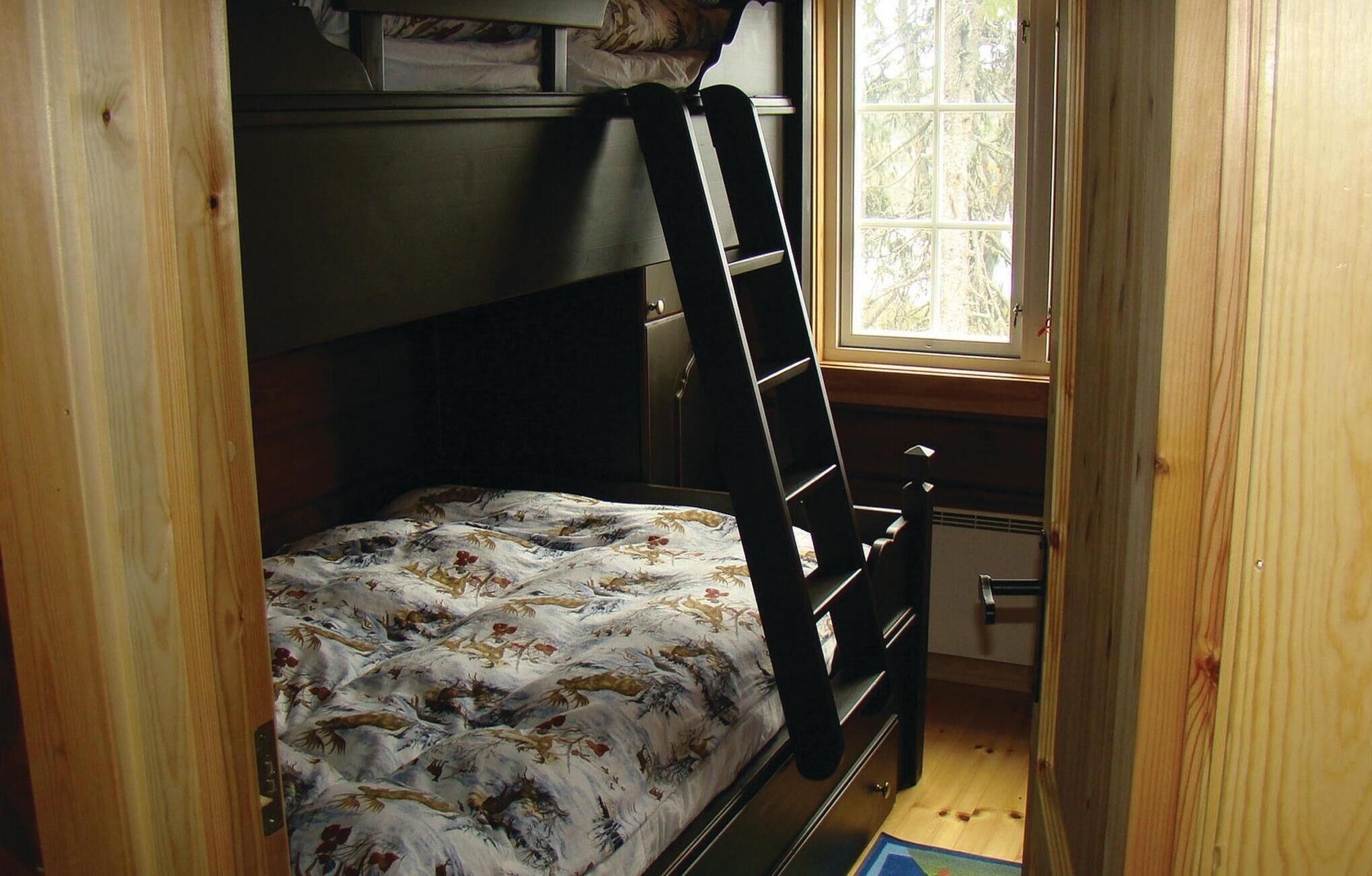 A small, narrow room with a bunk bed, a ladder, a window, and a door.