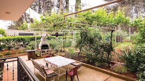 An outdoor patio with a stone pizza oven, a table, and chairs. - 2 bedroom awesome apartment in Fazana (Fazana)