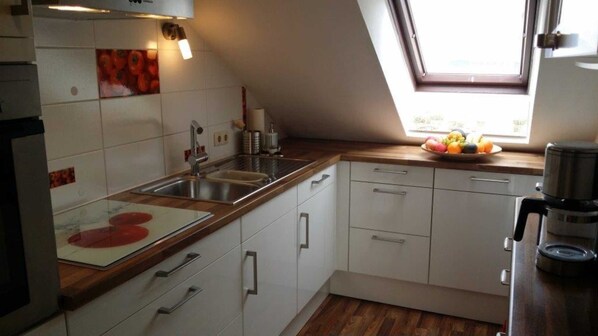 A kitchen with white cabinets, a wooden countertop, a sink, and a window with a view of the outdoors. - Fewo Groß - Holiday home Asel (Vöhl)