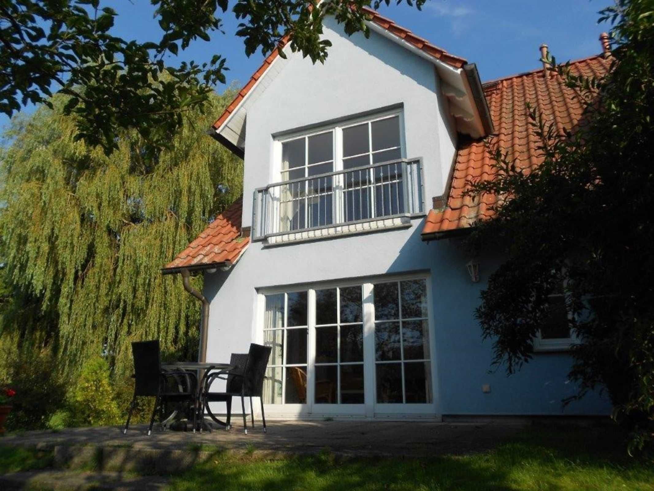 A two-story house with a balcony, large windows, and a tiled roof.