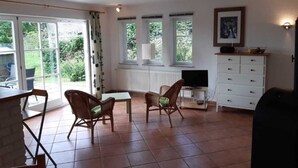 Amplia sala de estar con un ventanal, televisor y un mueble blanco.