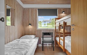 Ein Schlafzimmer mit Holzwänden, einem Fenster mit Blick und einem Schreibtisch sowie Etagenbetten.