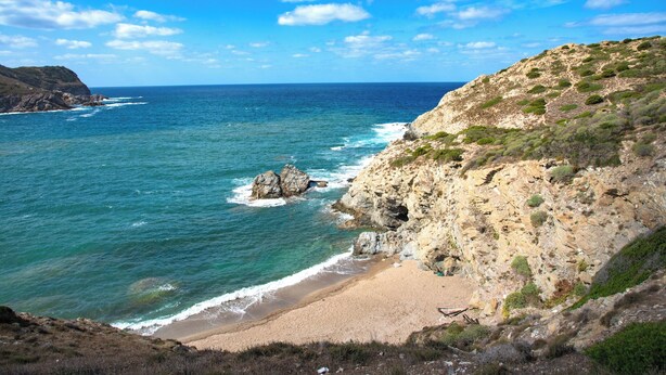 A coastal landscape with a beach, rocky cliffs, and the ocean. - Holiday home with air conditioning (Alghero)