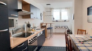 Une cuisine compacte équipée d’un four à micro-ondes, d’une cuisinière et d’un évier. Un coin repas avec une table et des chaises est également disponible.