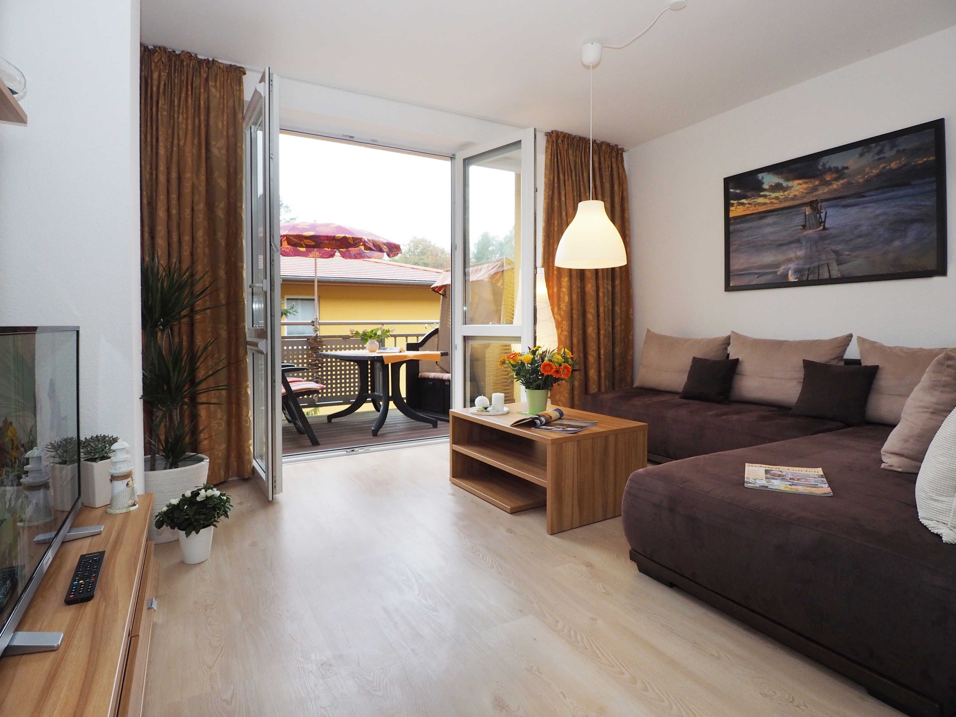 Een moderne woonkamer met een bruine bank, een houten salontafel en een eethoek met een tafel en stoelen.