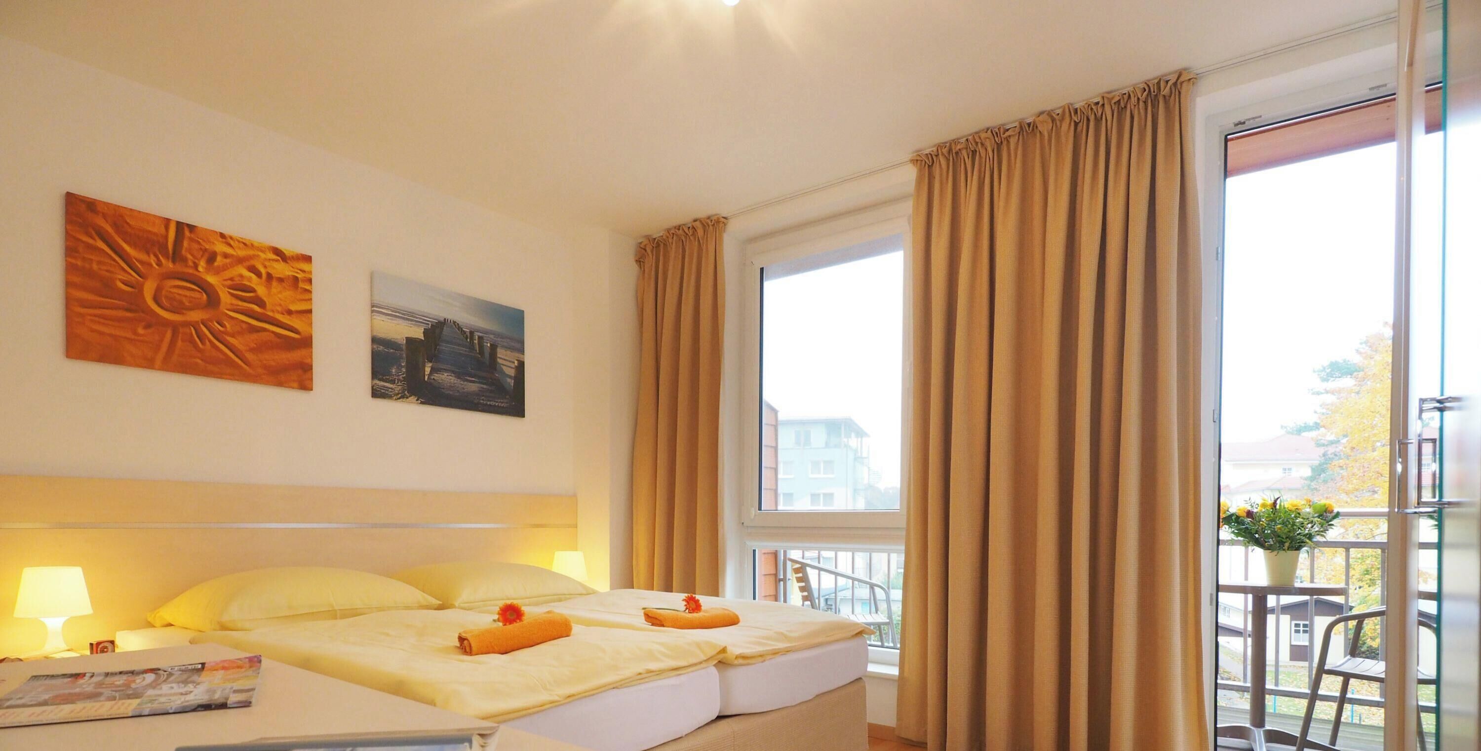 A hotel room with two beds, a balcony with a chair, and a large window with curtains.