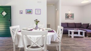 A dining area with a round table set for four, surrounded by white chairs with floral cushions. There are three framed artworks on the wall above the table. - Beautiful home in Hrvace (Hrvace)