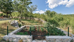 A garden with raised beds, a pergola, and a stone wall. - Beautiful home in Hrvace (Hrvace)