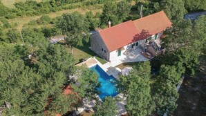 An aerial view of a stone house with a red roof, surrounded by lush greenery and a swimming pool. - Beautiful home in Hrvace (Hrvace)