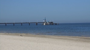 Eine Mole, die sich in ruhiges Wasser erstreckt, mit wolkenlosem Himmel.