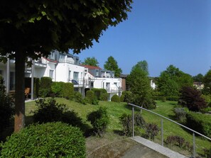 A residential area with modern buildings, a well-maintained lawn, and a metal railing.