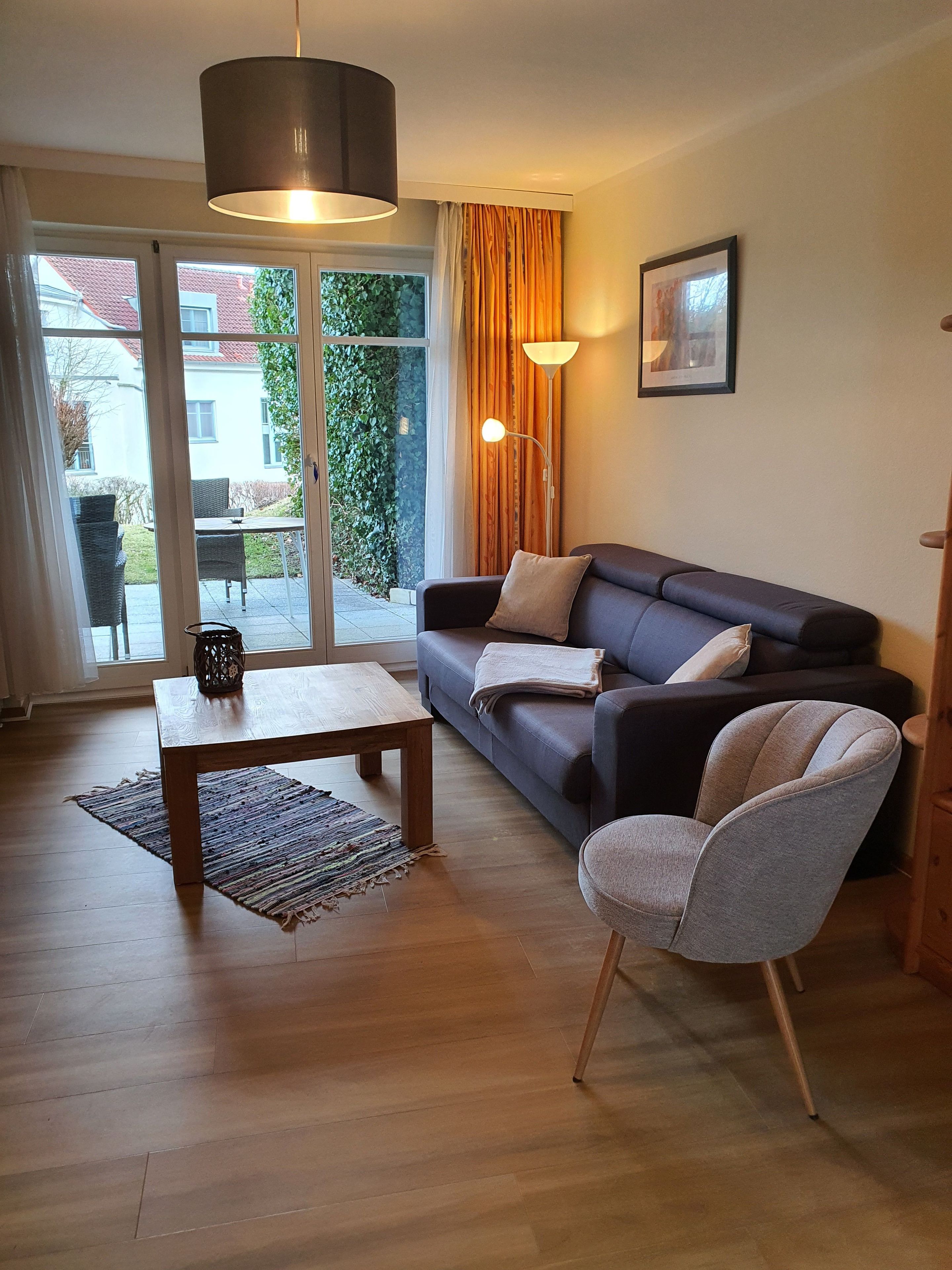 A living room with a sofa, a coffee table, a chair, a floor lamp, and a picture on the wall.