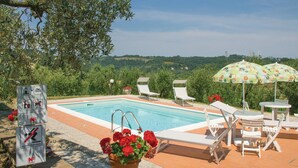Une piscine entourée de chaises longues et de parasols, bordée de verdure et offrant une vue pittoresque.
