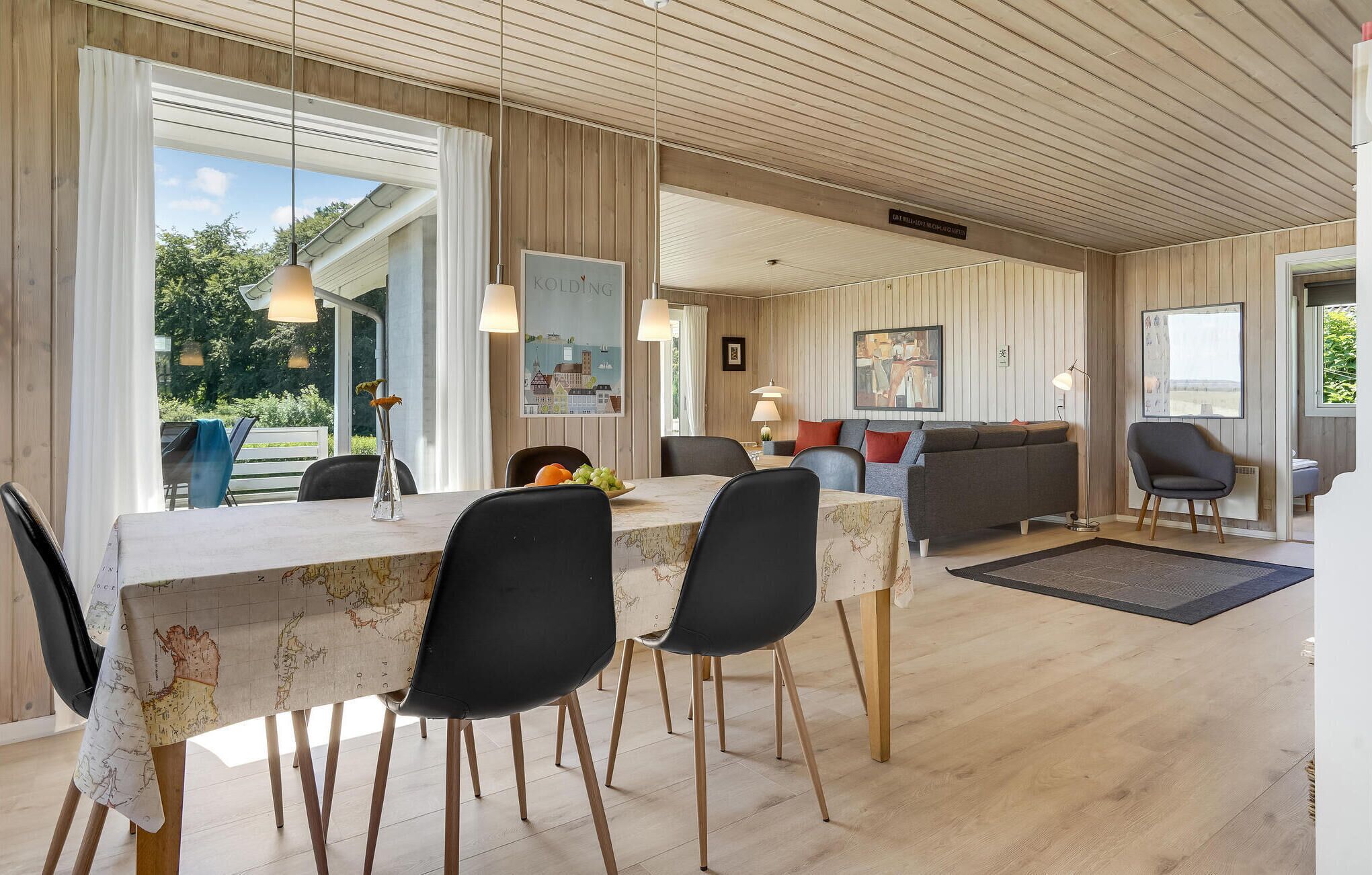 A dining area with a table set for four, a sofa, and a lamp.