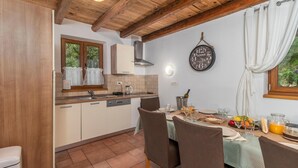 Una cocina con armarios de madera, un lavamanos y una zona de comedor con una mesa para dos.