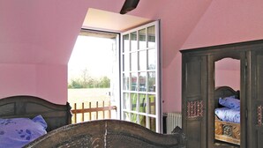 Un dormitorio con cama de madera, cómoda y ventana con vista a una valla y árboles.