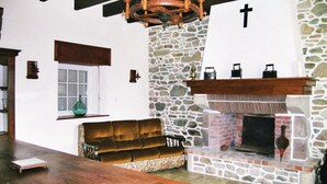 Un salón acogedor con chimenea de piedra, un banco de madera y un ventanal grande.
