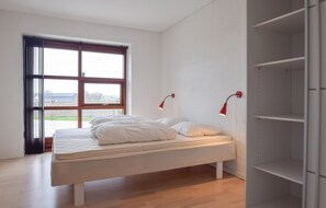A bedroom with a bed, a window, and a shelving unit.