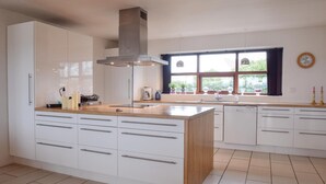 A modern kitchen with white cabinets, a wooden countertop, and a large window providing natural light. - 4 bedroom beautiful home in Humble (Humble)