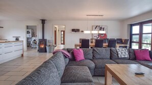 A modern living room with a sectional sofa, a wooden coffee table, and a kitchen area with a stove and washing machine. - 4 bedroom beautiful home in Humble (Humble)