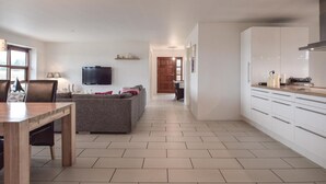 A modern kitchen with white cabinets and a dining area with a wooden table and chairs. - 4 bedroom beautiful home in Humble (Humble)