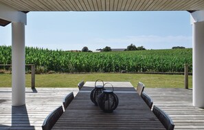 A covered outdoor area with a wooden deck, two chairs, and a decorative black object in the center.