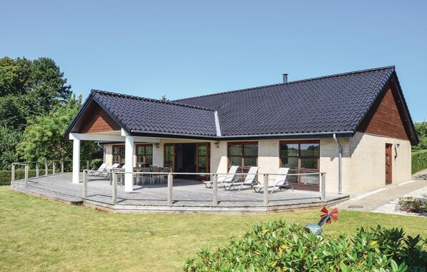A two-story house with a covered patio, a chimney, and a fenced garden area.