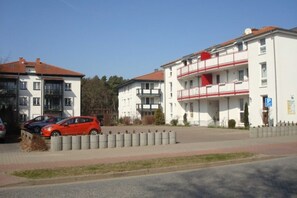 A residential building with a red car parked in front.