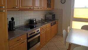 A kitchen with wooden cabinets, a microwave, a toaster, a kettle, and a sink.